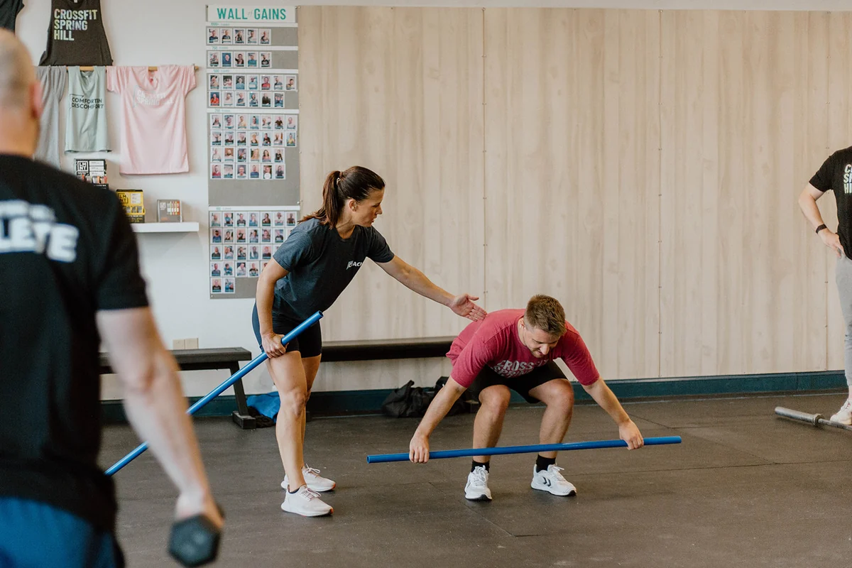 A CrossFit Spring Hill coach teaching a member the setup position with a PVC pipe before any weight is added