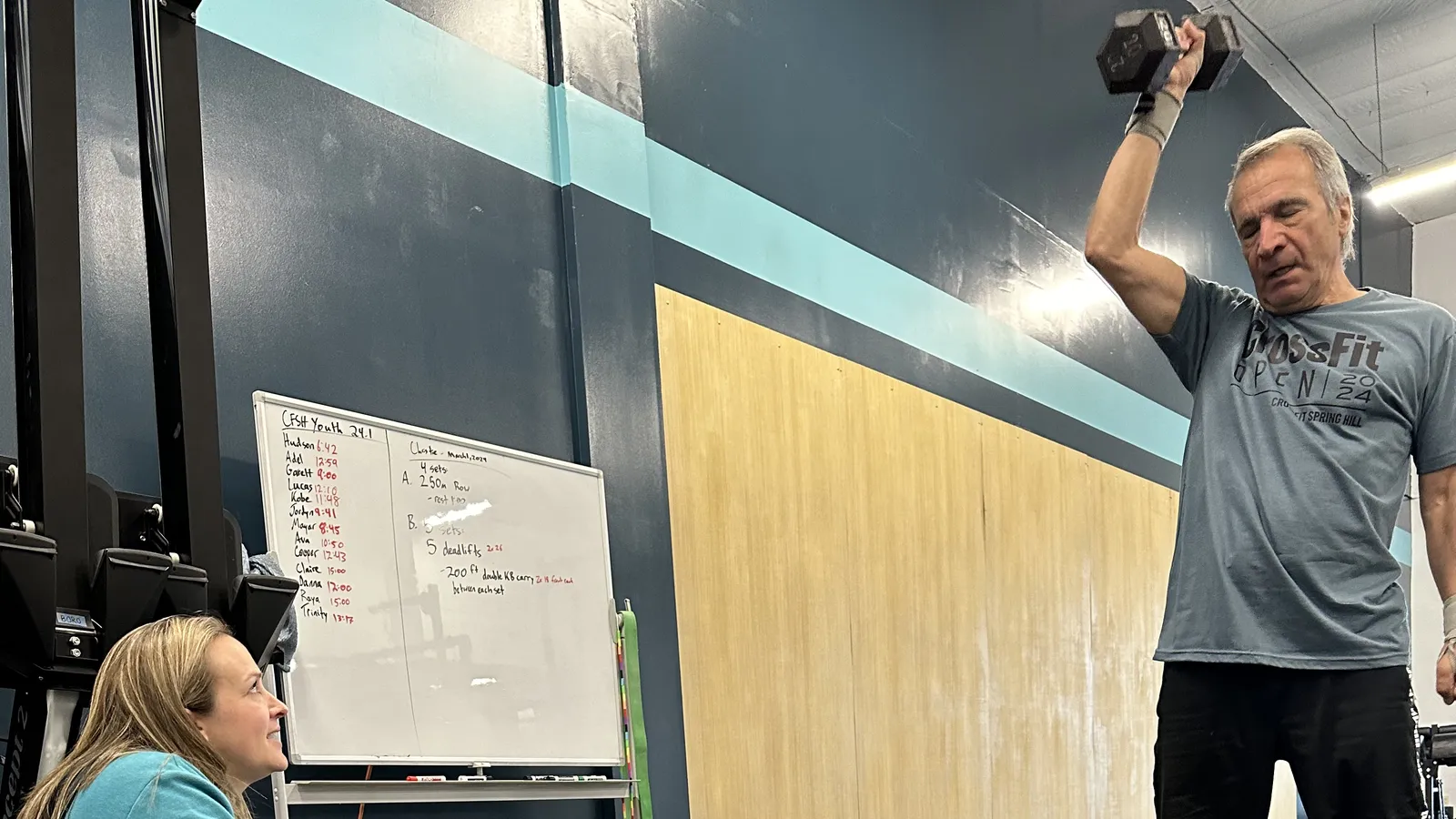 Coach Kim Butler coaching a Legends member through a dumbbell press at CrossFit Spring Hill