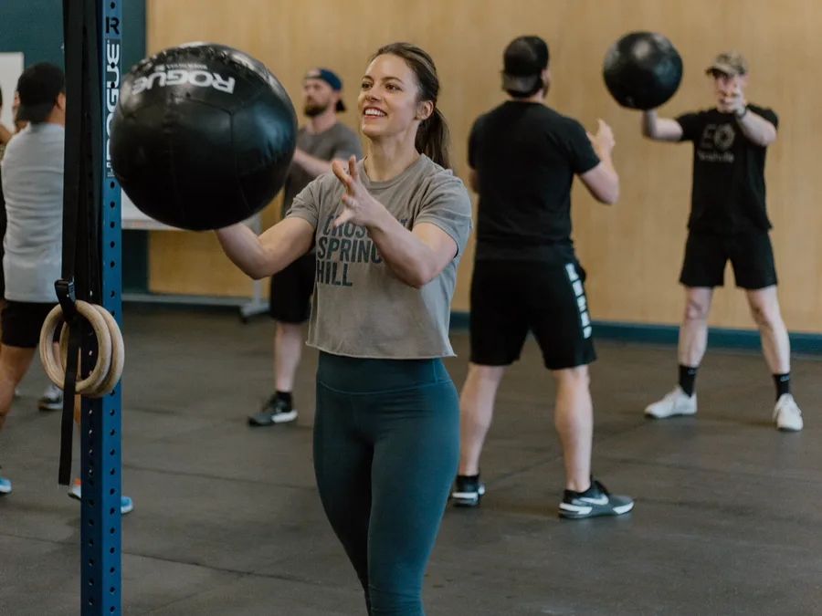 Member smiling mid med ball toss during a group class at CrossFit Spring Hill